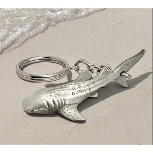 Un porte-clés en forme de requin-baleine repose sur le sable, évoquant l'exploration des profondeurs marines. #Plongée