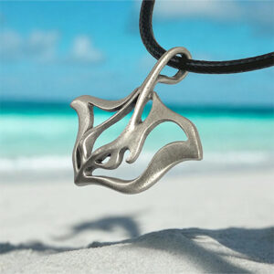 Bbbyrsj-pendentif-raie-manta-bijou-collier-de-mer-1 Un pendentif en forme de raie manta repose sur une plage exotique, symbolisant l'élégance et la liberté des océans. #Plongée