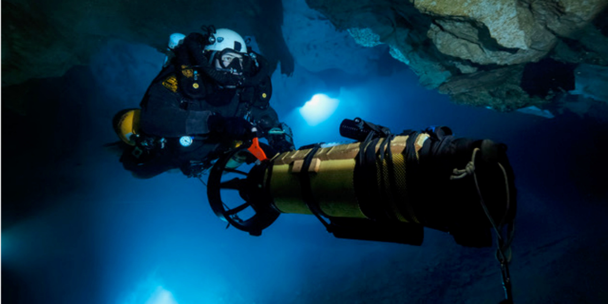 Plongée sous-marine avec équipement avancé dans une grotte aquatique illuminée.