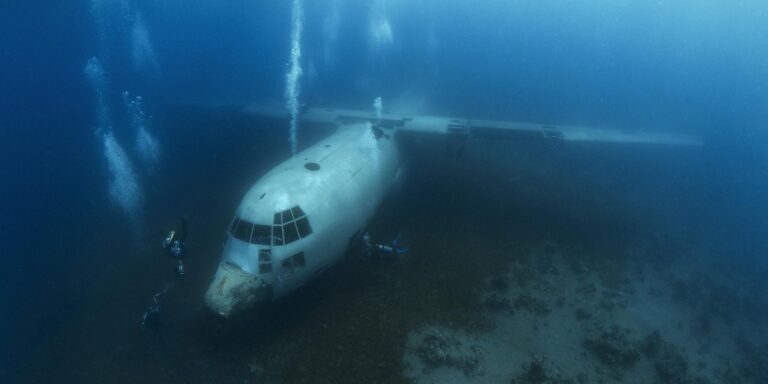 Epave d'avion sous-marin explorée par des plongeurs dans un environnement océanique fascinant.