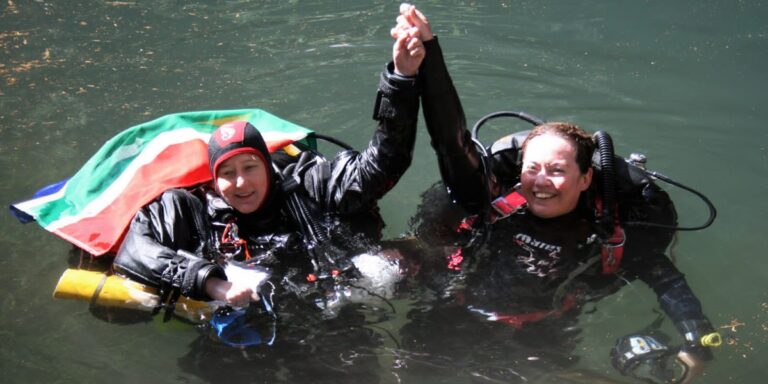 Deux plongeuses sous-marines s'amusent, vêtues de combinaisons de plongée. Exploration aquatique enrichissante.