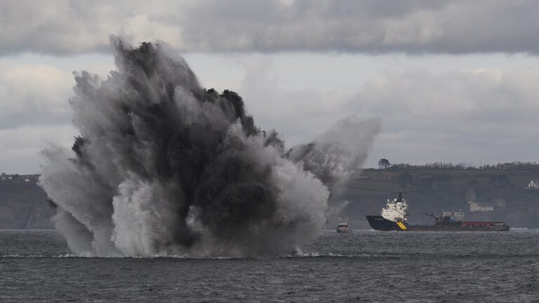 Explosion sous-marine spectaculaire avec navires en arrière-plan, illustrant la puissance de la mer.