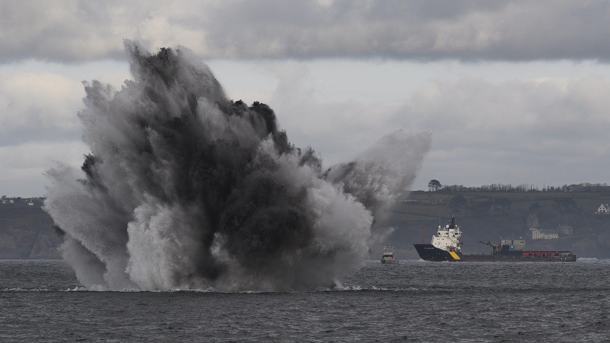 Explosion sous-marine spectaculaire avec navires en arrière-plan, illustrant la puissance de la mer.