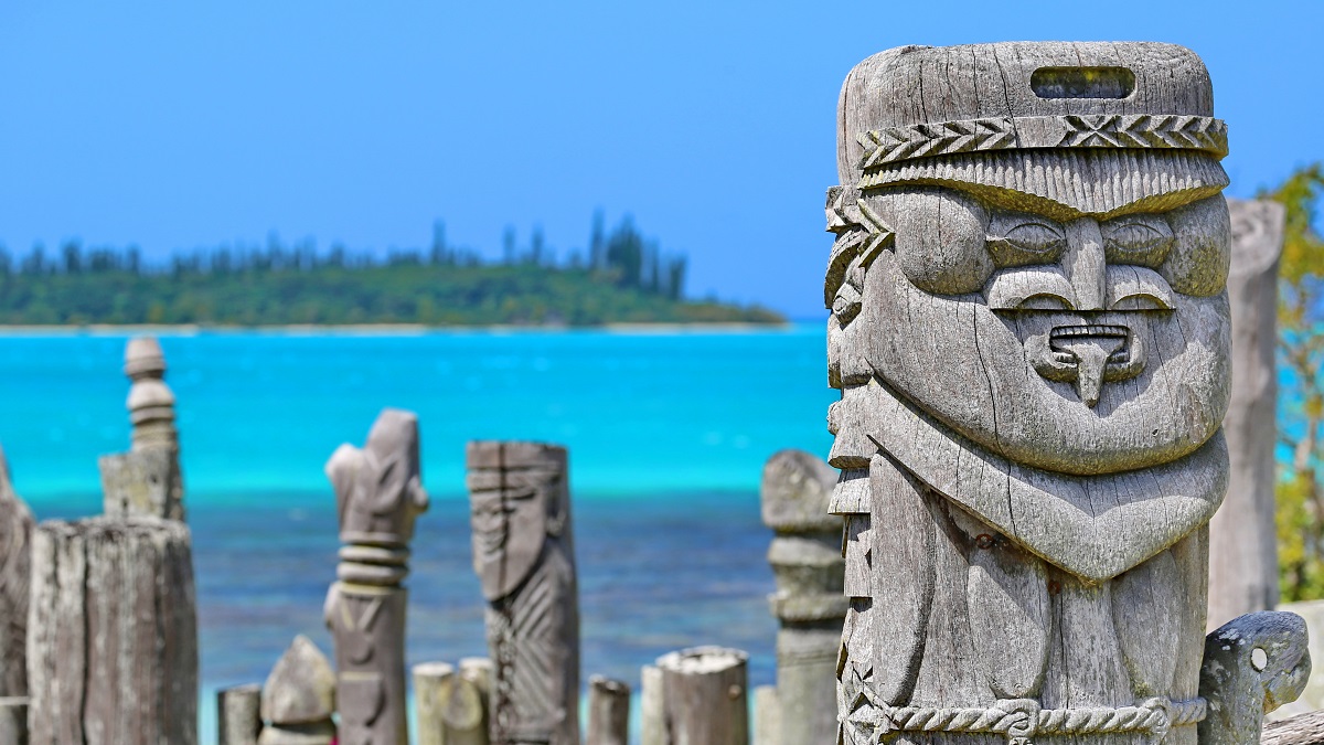 Statues en bois sculptées sur fond de lagon turquoise, symbole de culture océanique.