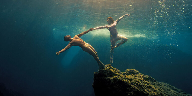 Deux plongeurs exécutent une danse gracieuse en apnée, suspendus dans les profondeurs bleues, illustrant l'harmonie marine.