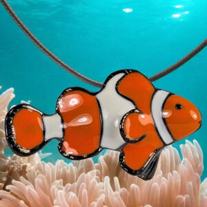 collier-poisson-clown Un pendentif en forme de poisson-clown flotte au-dessus d'une anémone, évoquant l'éclat coloré des récifs coralliens.