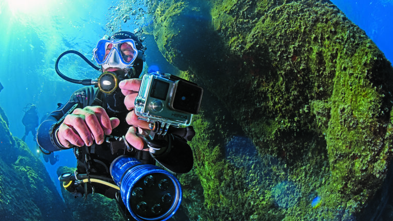Un plongeur explore les profondeurs marines, caméra à la main, capturant la beauté sous-marine pour des souvenirs d'aventu...