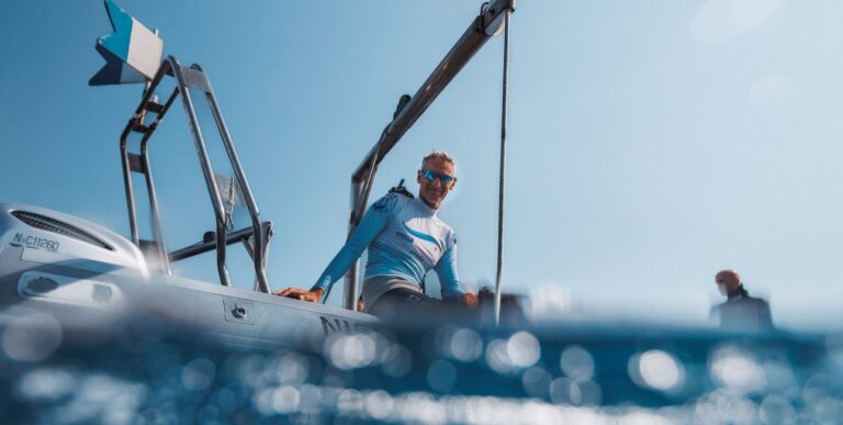 Un plongeur prépare son équipement sur un bateau sous un ciel bleu éclatant, prêt pour une aventure sous-marine exceptionn...