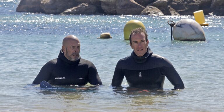 Deux plongeurs en combinaison discutent dans une eau cristalline, prêts à explorer les merveilles sous-marines. #Plongée