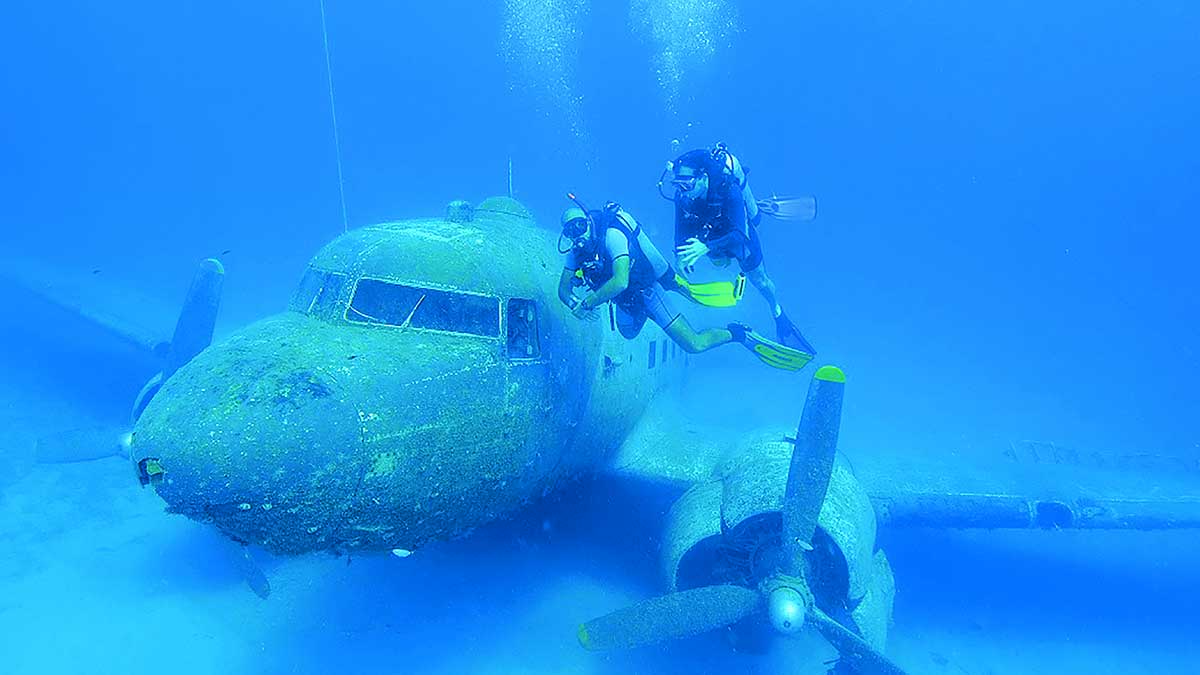 Deux plongeurs explorent l'épave d'un avion immergé, révélant un trésor caché de l'océan propice à l'aventure sous-marine.