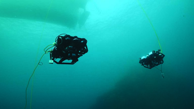Deux drones sous-marins explorent les profondeurs océaniques, illustrant l'innovation technologique en plongée.