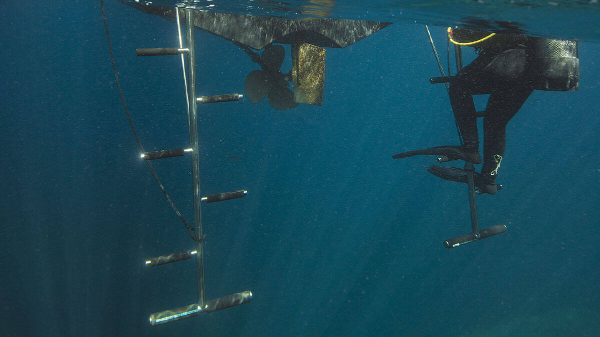 Un plongeur remonte prudemment l'échelle d'un bateau, illustrant l'importance de la sécurité en plongée sous-marine.