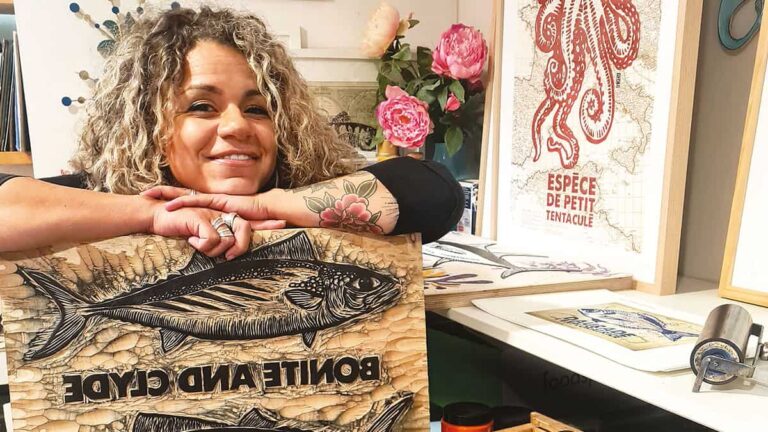 Une artiste souriante présente ses œuvres inspirées par la faune marine, soulignant la beauté et la diversité de l'océan.