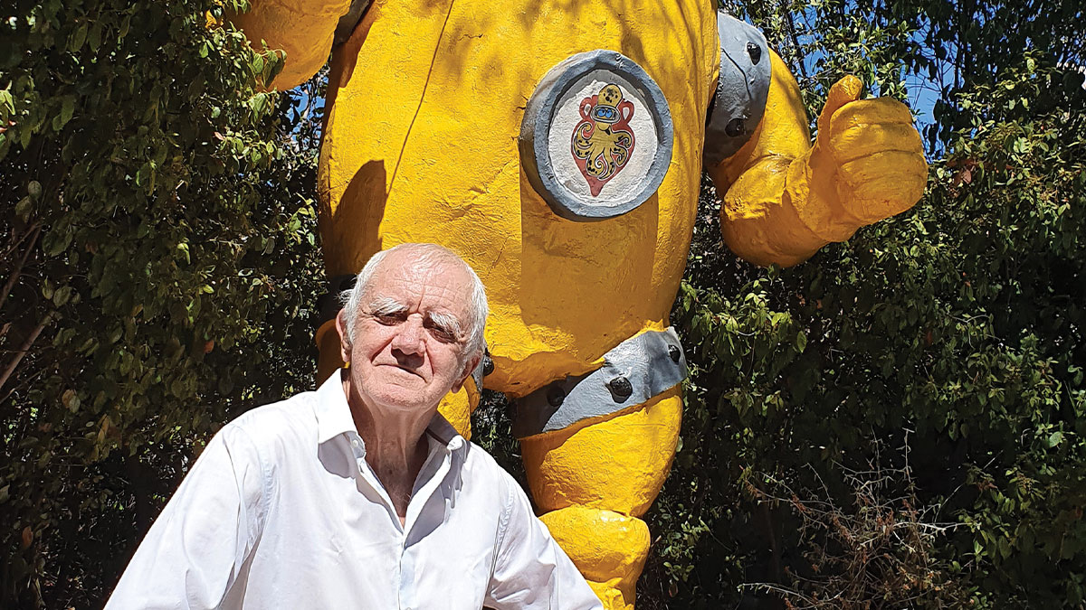 Un homme pose devant une statue géante de scaphandrier jaune, symbolisant l'exploration sous-marine. #Plongée