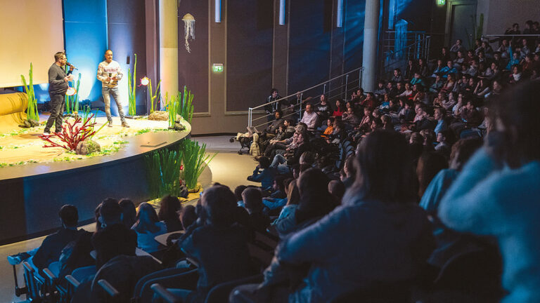 Un public captivé assiste à une conférence immersive sur la biodiversité marine lors d'un festival sous-marin. 🌊