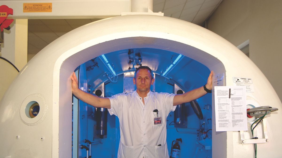 Un professionnel présente une chambre hyperbare, essentielle pour la sécurité des plongeurs et le traitement des accidents...