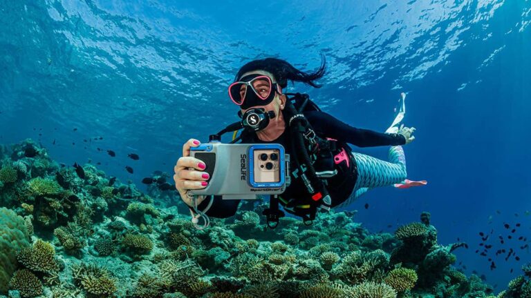 Une plongeuse capture la beauté des récifs coralliens, illustrant l'importance de la préservation marine.