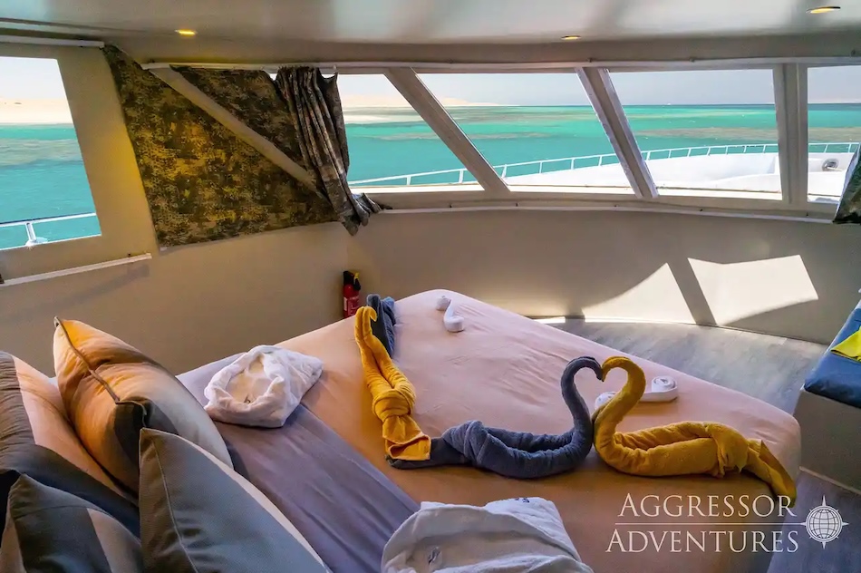 Cabine élégante sur un yacht avec vue sur la mer turquoise, serviettes en forme d’animaux.