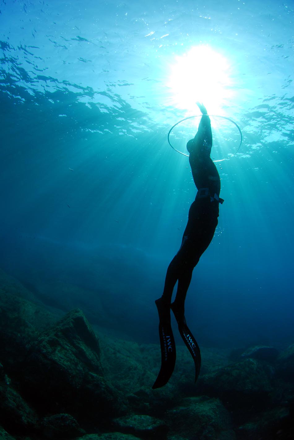 Plongeur en apnée s'élevant vers la surface, illuminé par les rayons du soleil sous-marin.