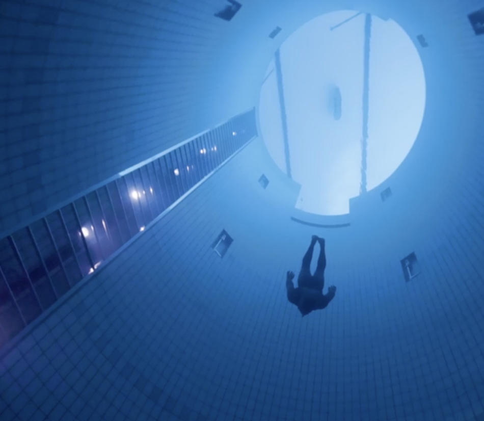 Un plongeur explore les profondeurs d'une piscine sous-marine, révélant l'univers aquatique fascinant.