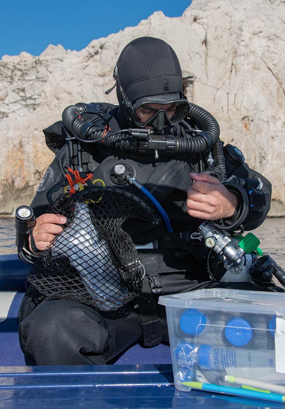 Plongeur préparant son équipement pour une exploration sous-marine dans un environnement côtier.