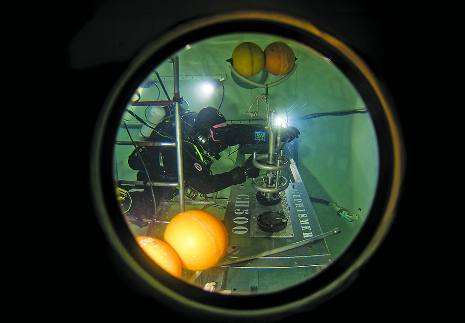 Un plongeur effectue des recherches sous-marines avec des équipements spécialisés dans un environnement aquatique.