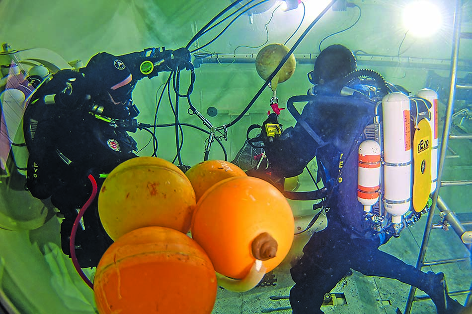 Des plongeurs équipés travaillent sous l'eau, utilisant des bouées pour des missions sous-marines.