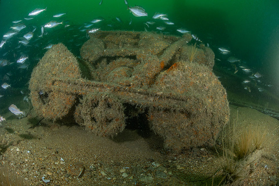 Un engin sous-marin recouvert d'algues, habité par des poissons, témoigne de l'exploration océanique.