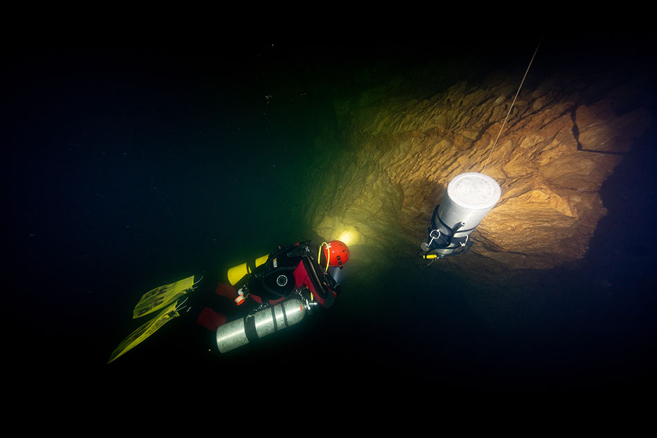 Un plongeur explore une cavité sous-marine, équipé d'un système de plongée avancé.