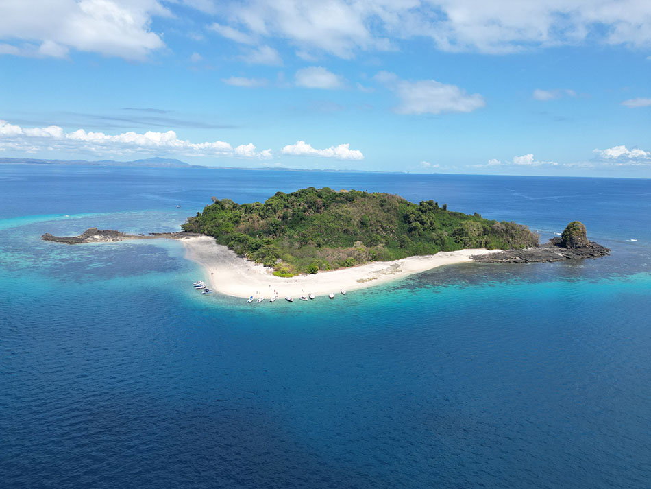 Île tropicale entourée d'eaux cristallines, idéale pour la plongée sous-marine et l'exploration marine.