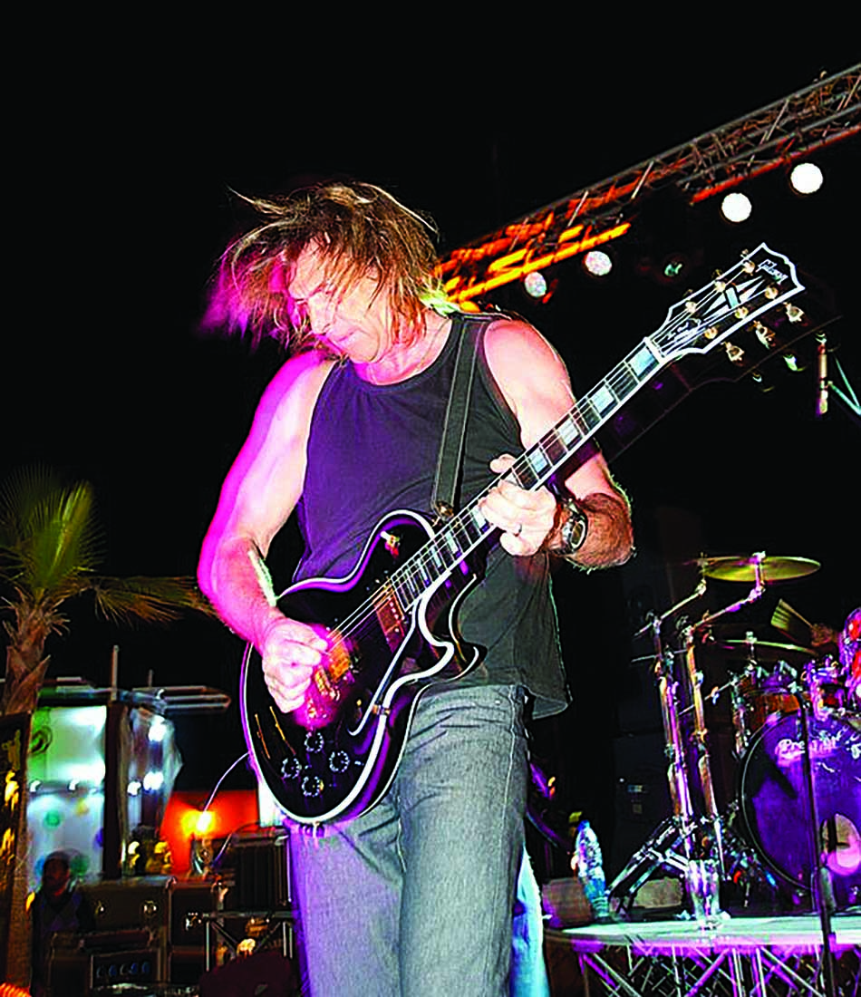 Un guitariste passionné animant un concert en bord de mer, évoquant l'énergie des soirées estivales.