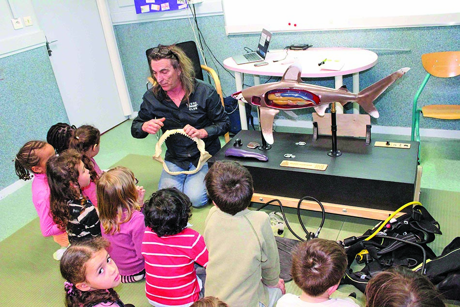 Un animateur explique la biologie marine aux enfants à l'aide d'un modèle de requin.