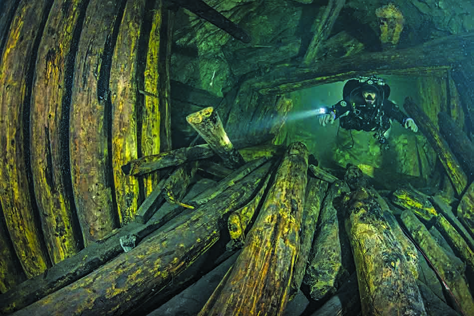 Plongée sous-marine dans une épave, révélant des structures en bois fascinantes et mystérieuses.
