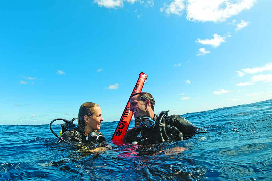 Deux plongeurs souriants profitent d'une journée en mer, prêts à explorer le monde sous-marin.