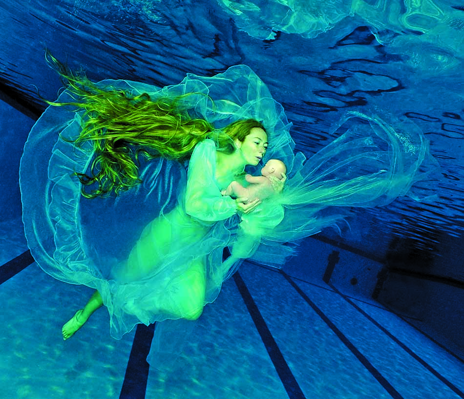 Une plongeuse en apnée évolue gracieusement sous l'eau, entourée de voiles fluides et colorés.