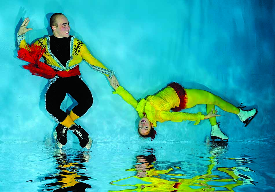 Artistes de patinage sur glace en pleine performance aquatique, évoquant l'univers sous-marin.