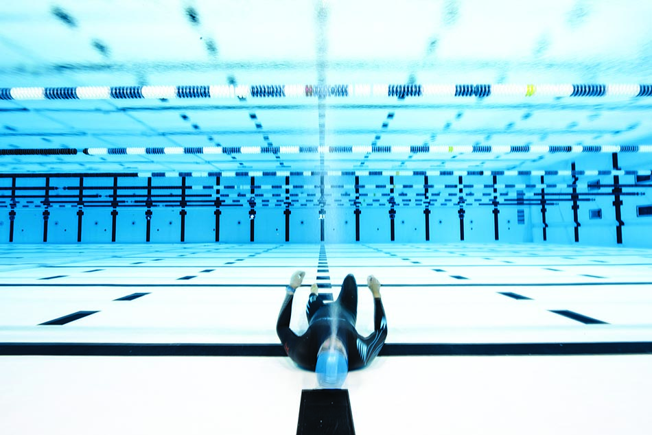 Un plongeur en apnée explore les profondeurs d'une piscine, mettant en avant la beauté du monde sous-marin.