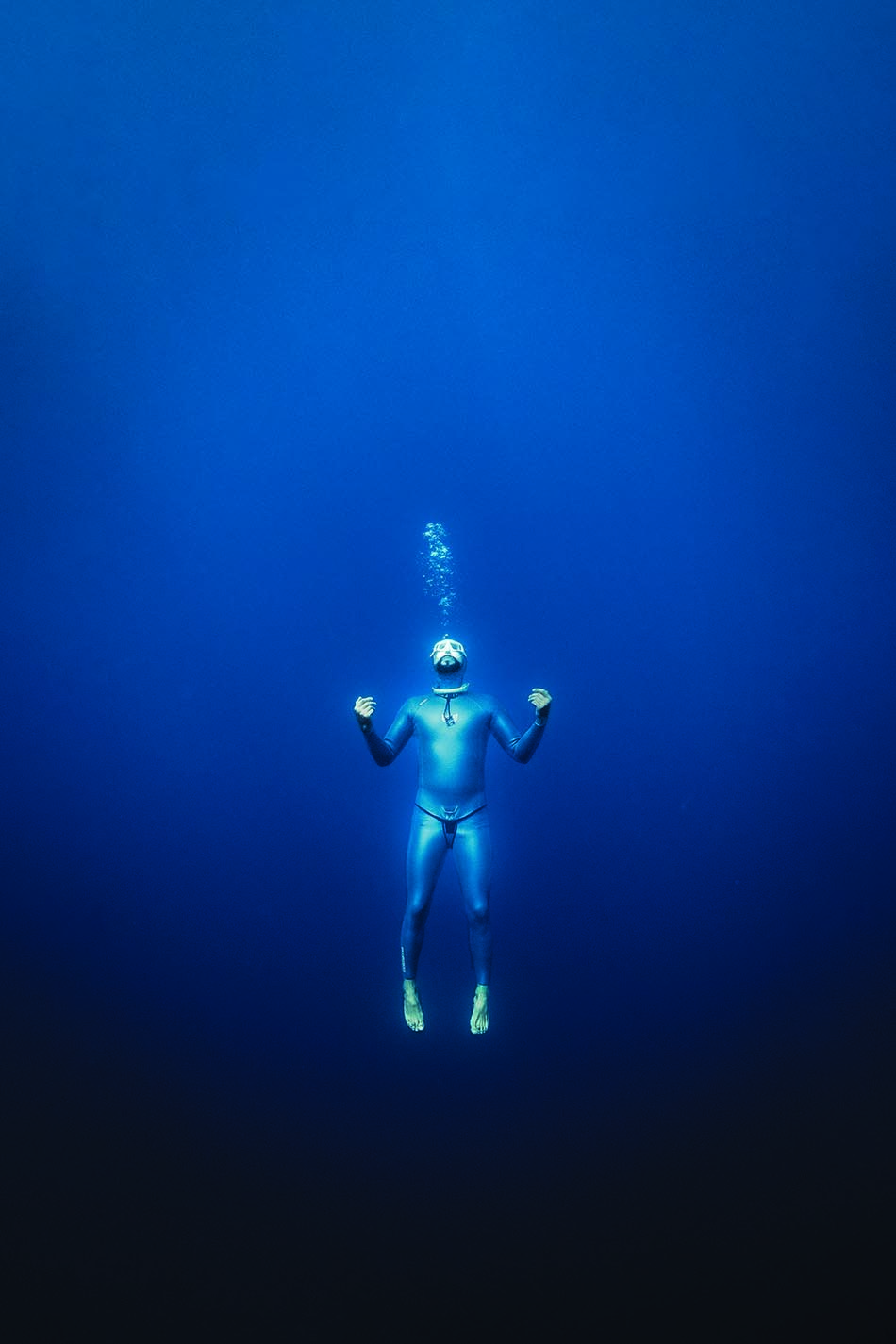 Plongeur en apnée évoluant dans les profondeurs marines, entouré d'un bleu intense.