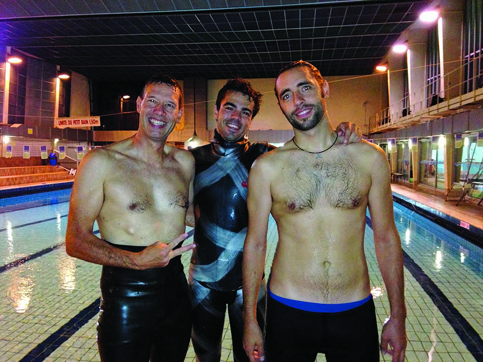 Trois plongeurs en apnée posent fièrement dans une piscine, prêts pour l'exploration sous-marine.