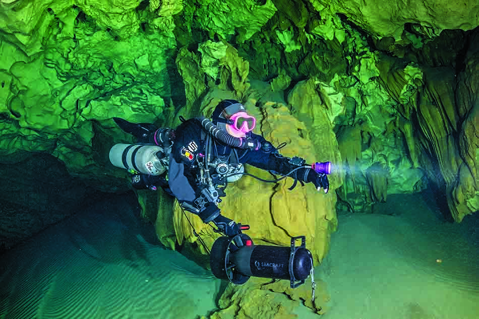Plongée dans une grotte sous-marine illuminée, révélant des formations rocheuses spectaculaires.