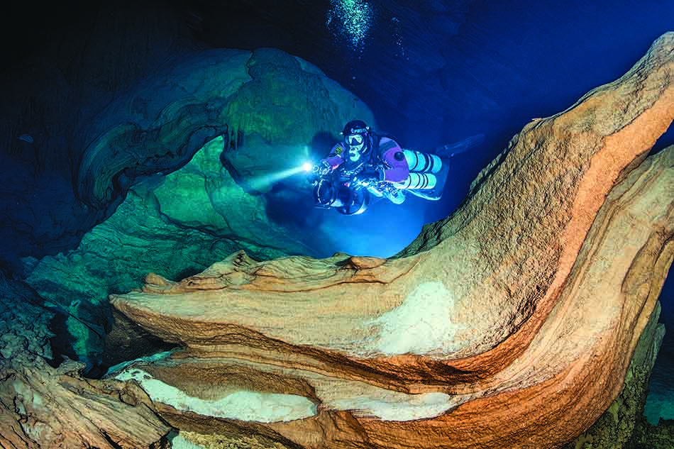 Plongeur explorant des formations rocheuses fascinantes dans un environnement sous-marin mystérieux.