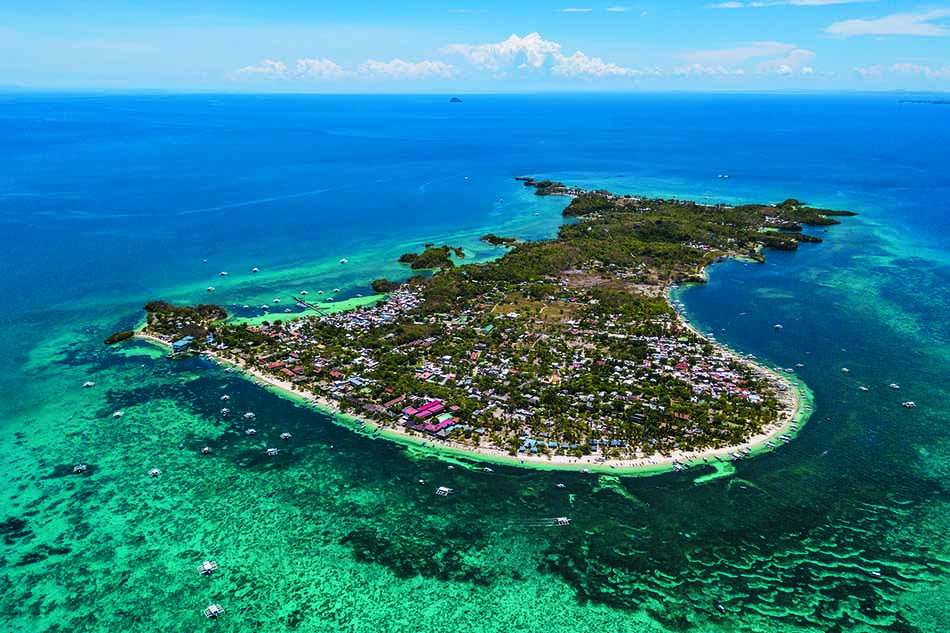 Île tropicale entourée d'eaux turquoise, idéale pour la plongée et l'exploration sous-marine.